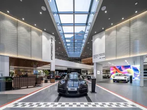 A sleek, modern car showroom with a steel, concrete, and glass interior showcasing a sports car on display.