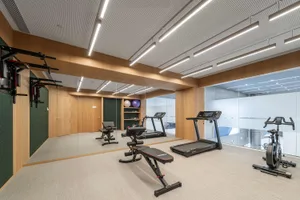A modern gym featuring wooden flooring, exercise equipment, and workout machines.