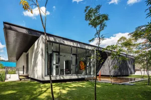A modern house with a concrete exterior and a glass front wall.
