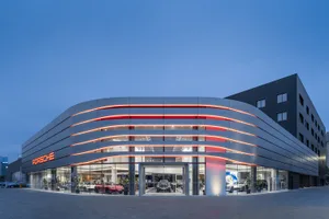 Modern Porsche showroom illuminated at night with red LED lighting and glass facade.