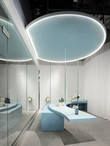 Minimalist retail store interior with blue concrete floor, matt white walls, and floral arrangements.