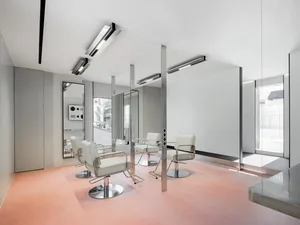 Modern, minimalist salon interior with metallic furniture and large mirrors.