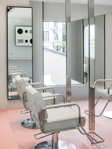 A modern commercial space featuring white leather chairs and mirrors.
