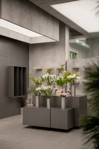 A modern concrete lobby featuring floral arrangements and minimalist furniture.