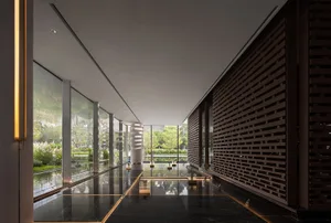 Modern lobby featuring glass walls and concrete flooring with a minimalist design.
