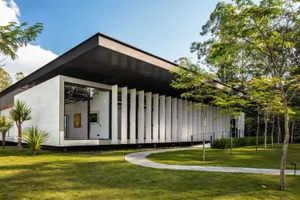 A modern minimalist house featuring expansive glass walls and concrete structural elements.