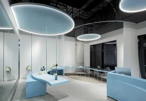 A modern office space with concrete walls, a curved table, and upper lights.
