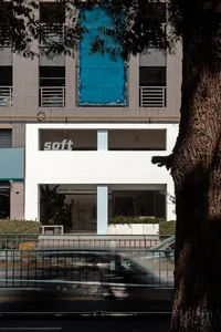 An exterior view of a modern retail storefront featuring large glass windows and a concrete base.