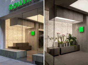 Modern minimalist lobby with concrete walls, seating area, and decorative greenery.