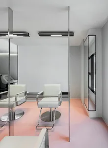 Modern minimalist salon interior with white chairs, glass walls, and pink flooring.