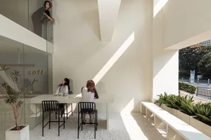 A modern office space featuring minimalist design with concrete and glass materials.