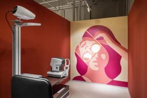 Modern examination room within a healthcare facility with industrial design elements, featuring a mural of someone adjusting 
