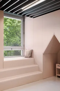 A minimalist children's space with wood elements and a window showing greenery outside.