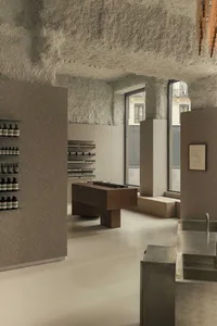 An interior retail store with minimalist design, concrete walls, and shelves filled with products.
