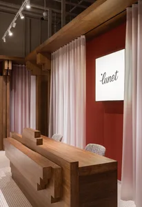 A modern interior design with a wooden reception counter featuring geometric shapes and a red background with curtains.
