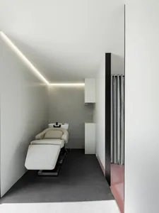 A modern interior spa treatment room with white walls, black flooring, and minimalist design elements.
