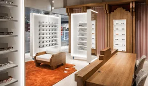 現代眼鏡店室內設計，採用木質家具、層架與玻璃展示櫃，並以柔和燈光照亮