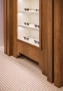 Modern retail store display featuring sunglasses on wooden shelves with white lighting.
