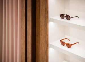 Pair of sunglasses on white wooden shelves in a retail display setting.