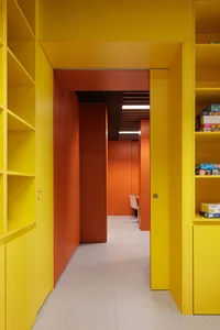 A vibrant hallway with bright yellow walls and orange doors.