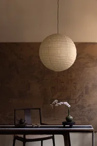 A minimalist living room featuring a white paper lantern hanging from the ceiling, creating a warm and inviting atmosphere.
