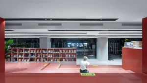 person sitting on a red concrete floor in a modern library reading room.