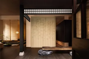 A living room with a transparent glass wall and minimalist design, featuring a wooden bench and stone base.
