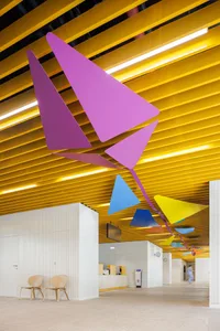 An office space featuring modern metal structures with colorful geometric shapes hanging from the ceiling.