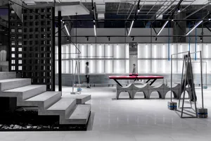 A spacious, modern sports gymnasium with concrete walls and a ping pong table.
