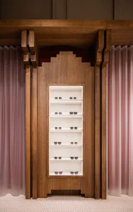 A wooden framed retail display with white shelving holding sunglasses.