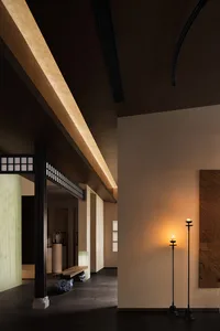 A modern lobby featuring plaster and glass materials, with warm lighting and minimalist design.