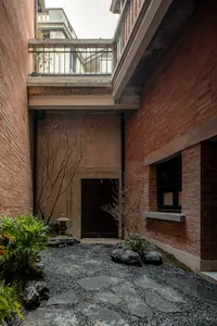 Concrete garden with rock formations and a modern entrance door.