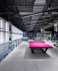 A minimalist playroom featuring concrete and glass materials with a vibrant pink ping pong table.