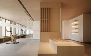 A modern fitness center featuring light-colored wood walls and glass partitions with exercise bikes and treadmills visible th