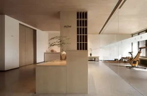 Interior view of a minimalist fitness center with wood-paneled walls and floors, featuring a reception desk and exercise equi