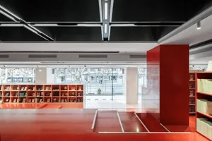 Modern industrial-style library with red metallic flooring and concrete structural columns.