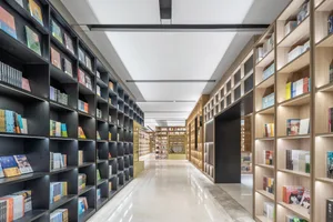 現代書店內有高聳的木製書架，架上擺滿書籍，並搭配玻璃牆面。
