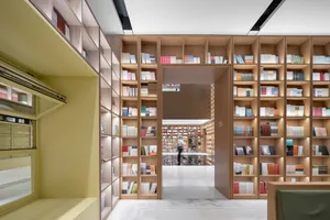 A modern library with a minimalist design and wooden shelves filled with books.