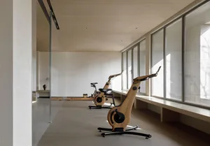 A minimalist fitness center featuring wooden stationary bikes with a view.