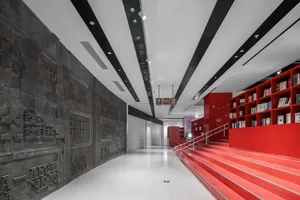 A modern library with red shelving units and concrete walls.