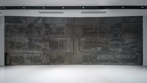 A dark metal mural featuring the words 'The Books Are the Steps of the Human Progress' in various languages