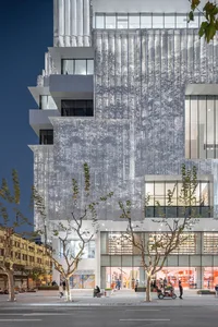 Modern shopping center exterior with glass panel cladding reflecting surroundings.