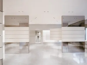 A minimalist exhibition hall featuring glass, metal, and concrete materials.
