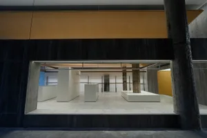 Minimalist art installation featuring a concrete structure within a gallery space.
