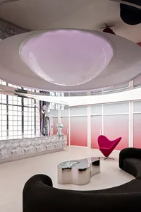 A modern lobby featuring metallic furniture and a large, circular light fixture.