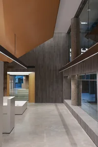 A minimalist office interior with a concrete floor, ceiling panels, and structural elements.