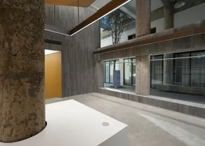 A contemporary office space with concrete walls and floors, featuring a minimalist interior design.