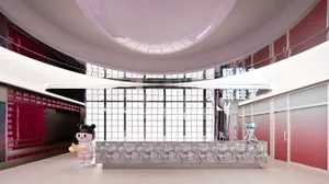 A modern shopping mall interior with a silver metallic counter, glass walls, and fabric finishes.