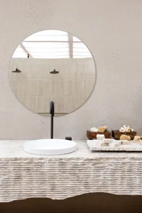 A minimalist bathroom with a concrete sink, round mirror, and natural lighting.