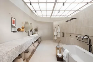 Modern minimalist bathroom with concrete, wood, and metal finishes featuring a freestanding bathtub, sinks, and a skylight ce